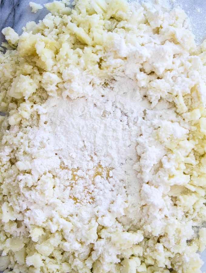 Homemade Italian Gnocchi ingredients are combined on a surface to make the dough.