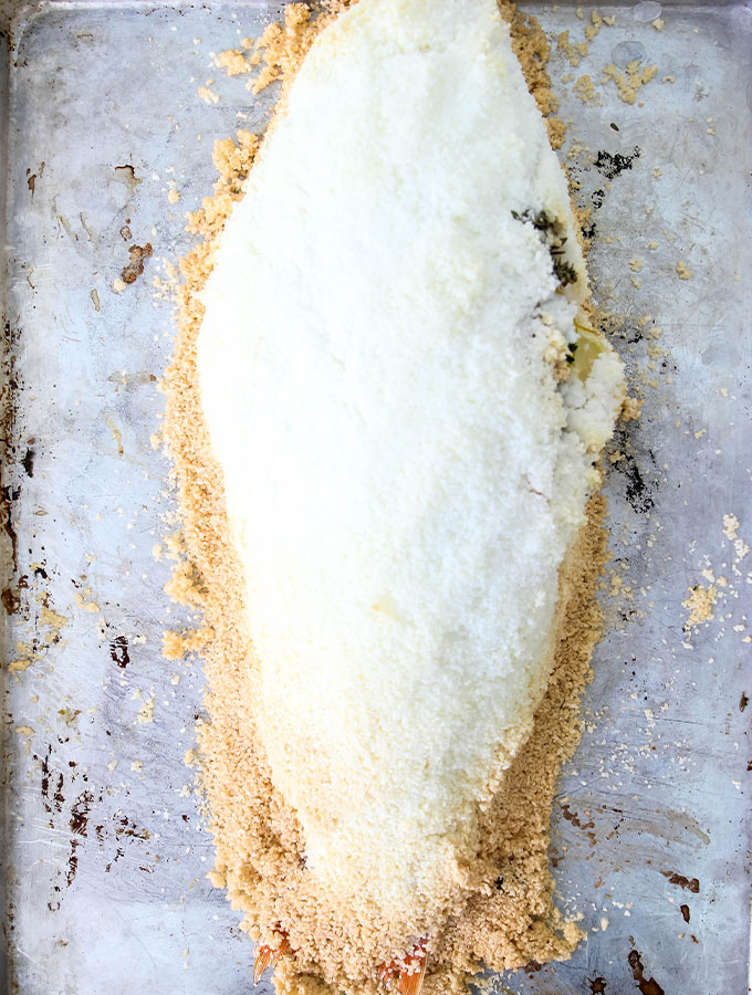 Salt Crusted Fish is baked on a baking sheet for 20 minutes until the edges are golden.