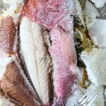 The fish skin is peeled back to expose the Salt Crusted Fish meat.