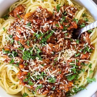 Bolognese Sauce is on top of spaghetti pasta with parmesan cheese.