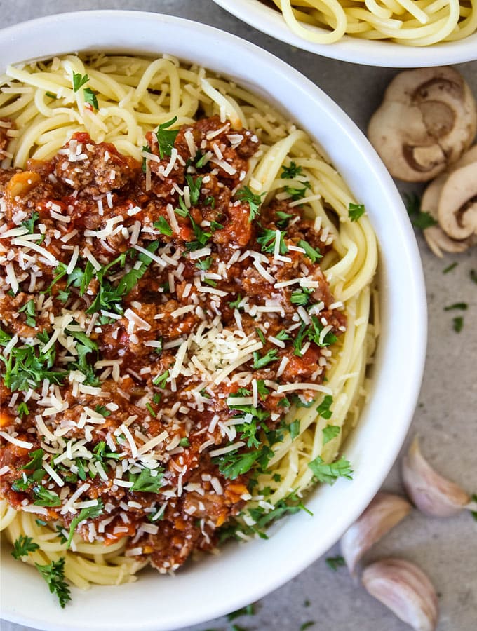 Authentic Bolognese Sauce is placed on top of spaghetti in a white bowl.