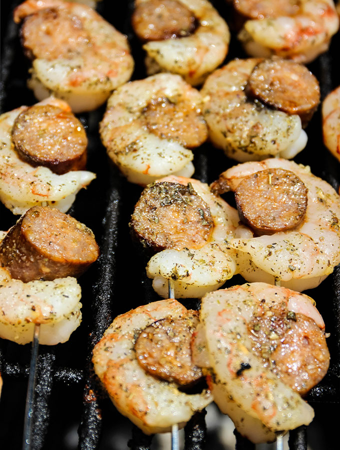 Grilled Italian Sausage and Shrimp Kabobs is placed on the grill to cook.