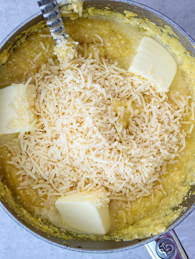 Polenta is made in a pot and topped with butter and parmesan cheese.