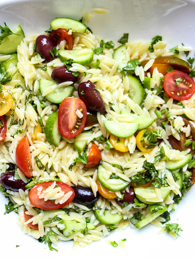 Italian Lemon Orzo Salad is tossed together in a white bowl.