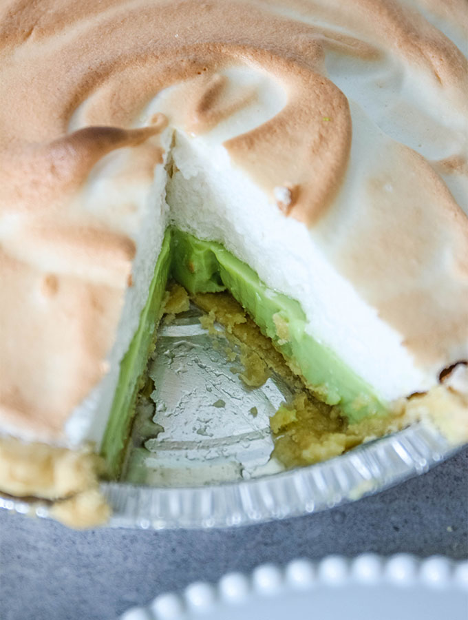 A slice is cut out of an authentic key lime pie.