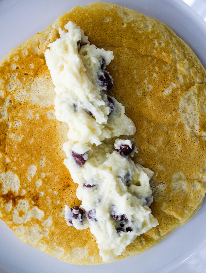 Cannoli filling is placed in the center of a buttermilk pancake before its rolled up.