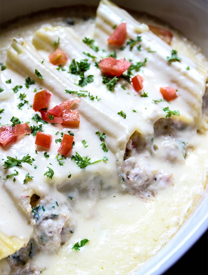 Crab Stuffed Manicotti with Alfredo Sauce is topped with alfredo sauce then baked in a dish.