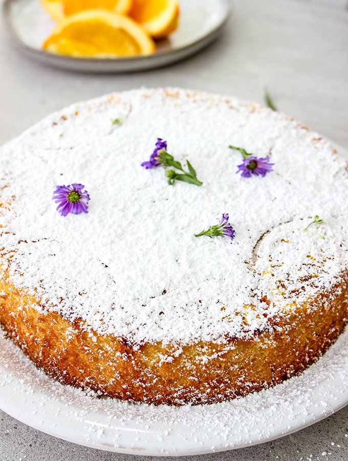 Easy Italian Olive Oil Cake is topped with sugar and flowers.