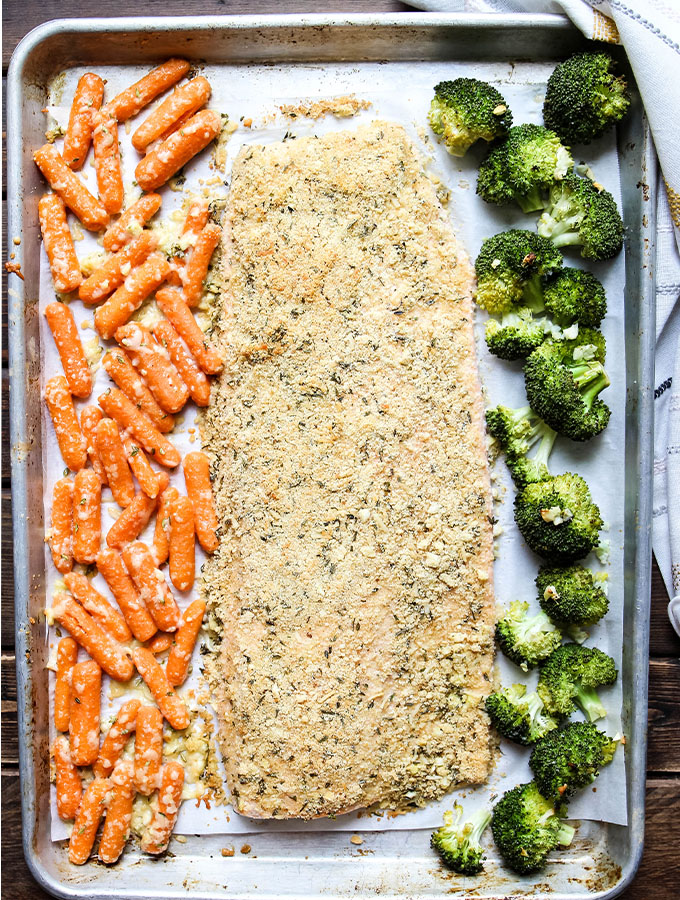 Salmon is cooked on a sheet pan with broccoli and carrots to save time.