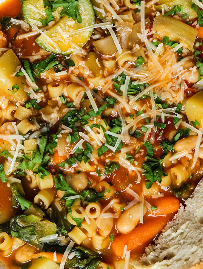 Minestrone soup is made in out pot, then topped with parmesan cheese and fresh herbs.