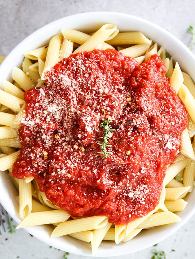 Easy Five Minute Marinara Sauce is placed over penne pasta and topped with parmesan cheese.