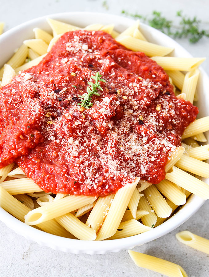 Easy Five Minute Marinara Sauce is placed over cooked penne pasta and topped with cheese.