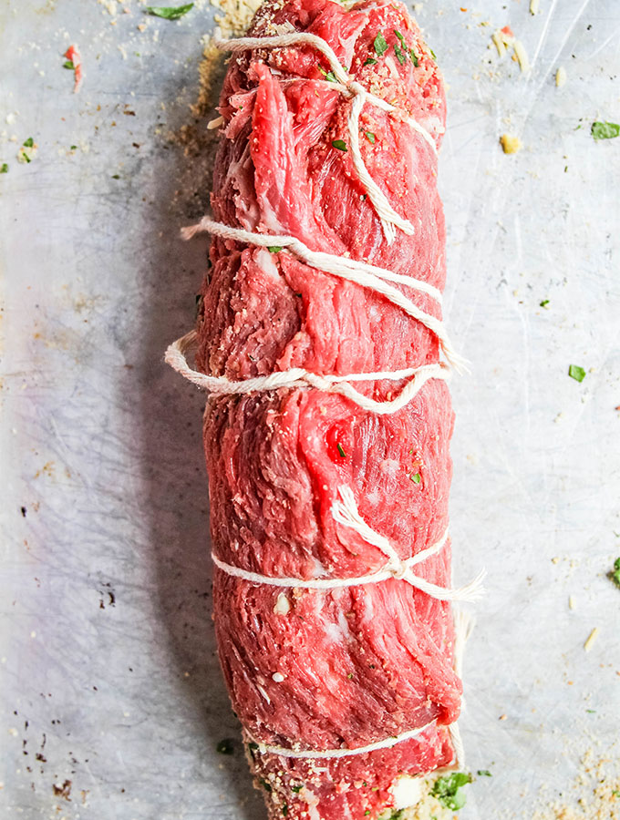 rolled up steak meat with strings holding it closed in a roll