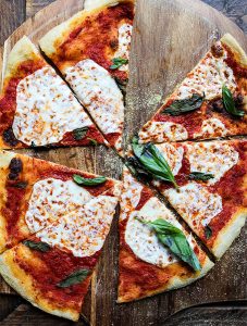 Margherita Pizza is sliced into triangles on a wooden pizza peel.the pizza peel.