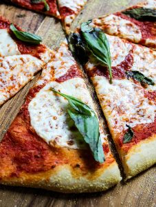 Margherita Pizza is sliced into triangles and topped with fresh basil.