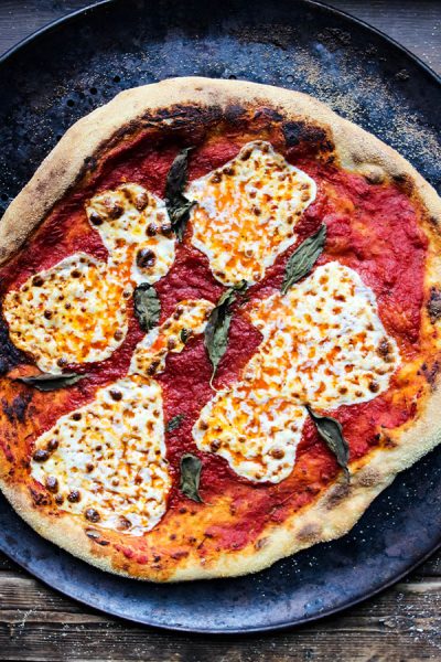 Margherita pizza is cooked on a pizza pan until it is crisped around the edges.