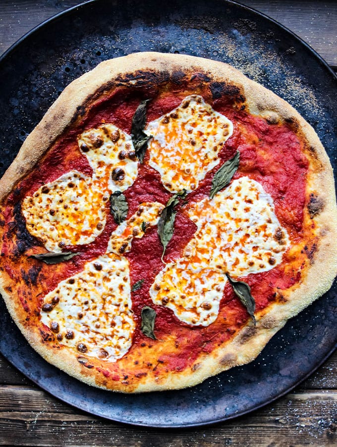 Margherita pizza is cooked on a pizza pan until it is crisped around the edges.