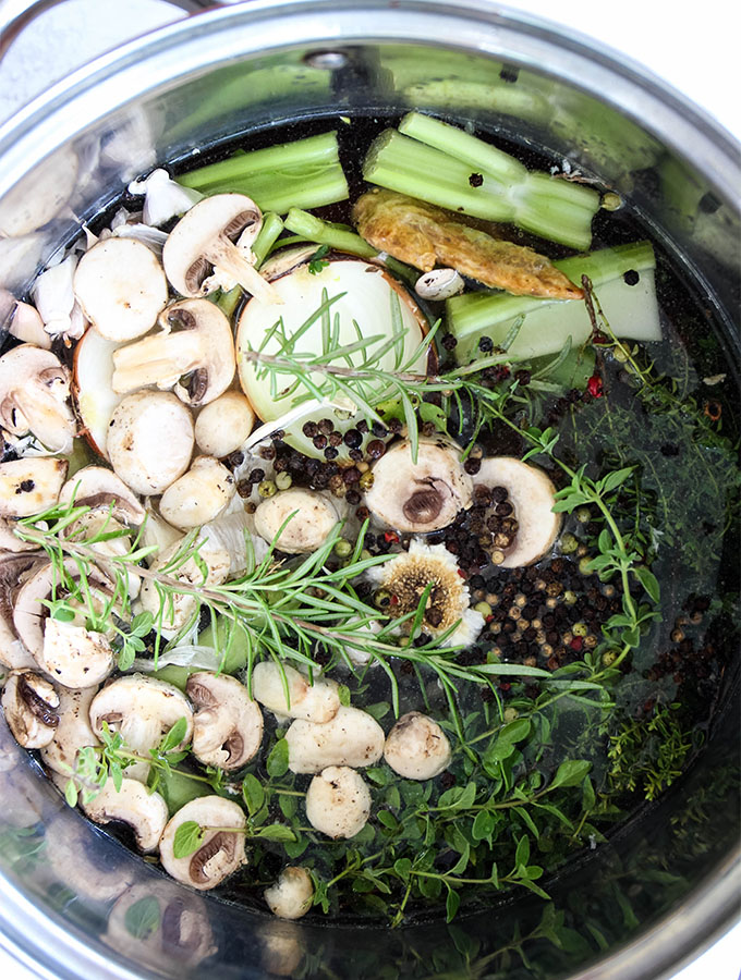 Vegetables, fresh herbs, spices, and chicken is combined in a large stockpot to make bone broth.