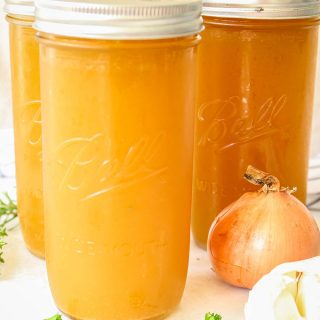 Chicken bone broth is poured into a few glass jars and topped with a lid before they are frozen.