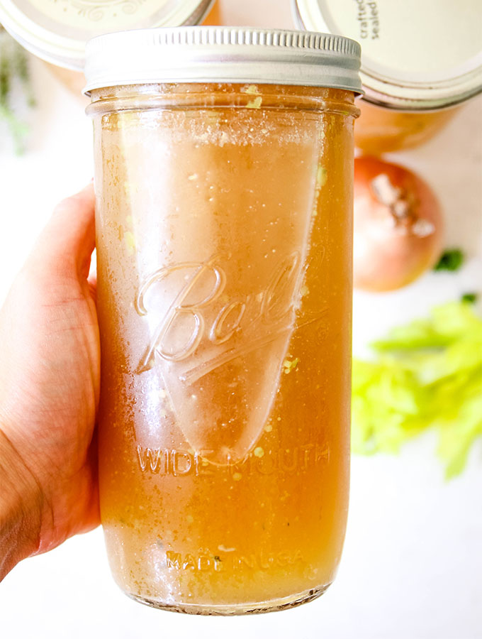 Chicken Bone Broth is poured into Mason Jars and topped with a lid to be stored in the freezer.
