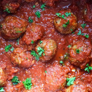 Italian meatballs are simmered in tomato sauce and topped with fresh parsley for garnish.