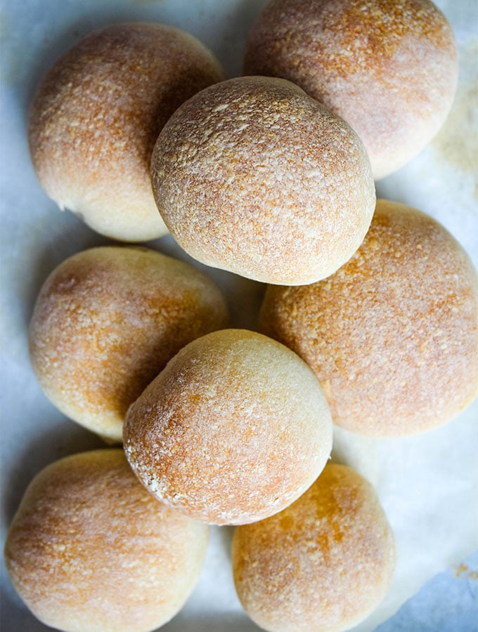 The French bread rolls are stacked onto of eachother on parchment paper.