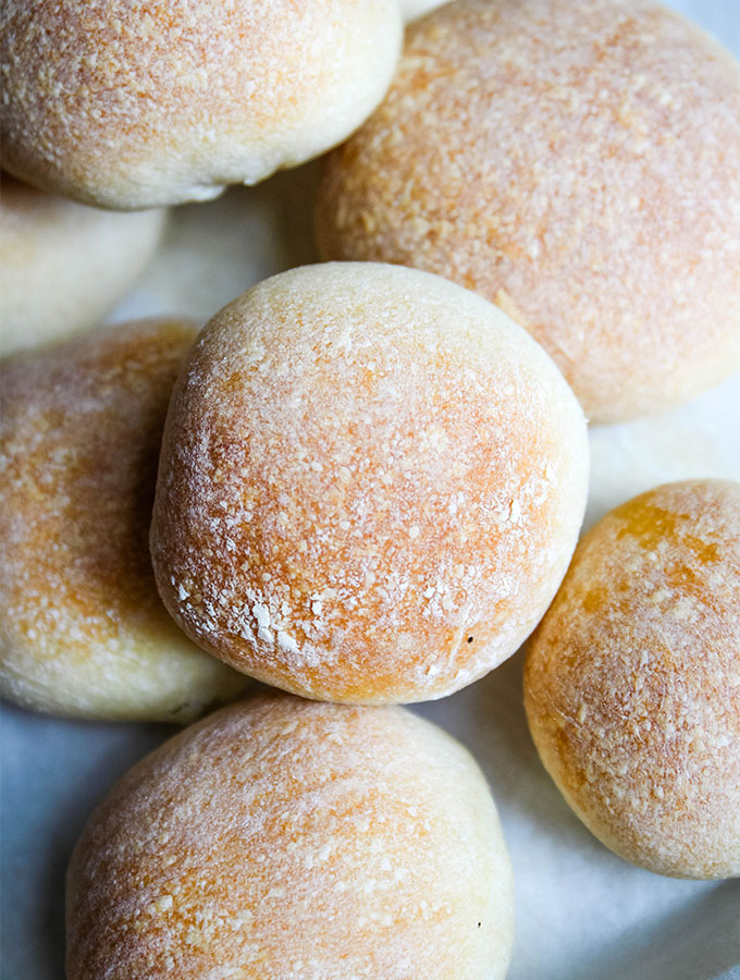 The French bread rolls are stacked on parchment paper.