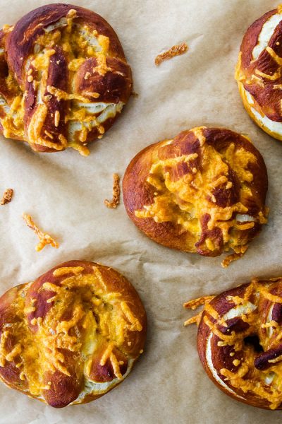 The soft pretzels are topped with cheddar cheese and baked until the cheese is golden brown and melted.