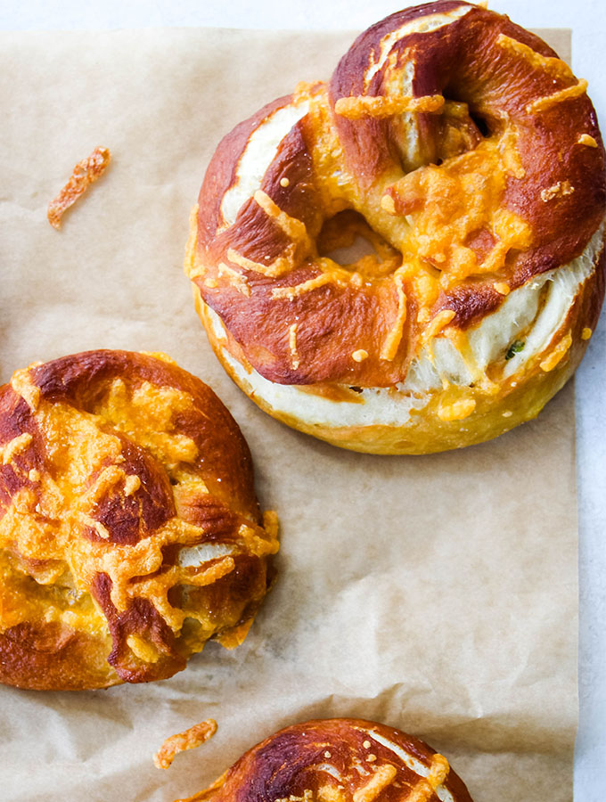 A soft pretzel is bursting at the seem with the jalapeno popper stufifng.