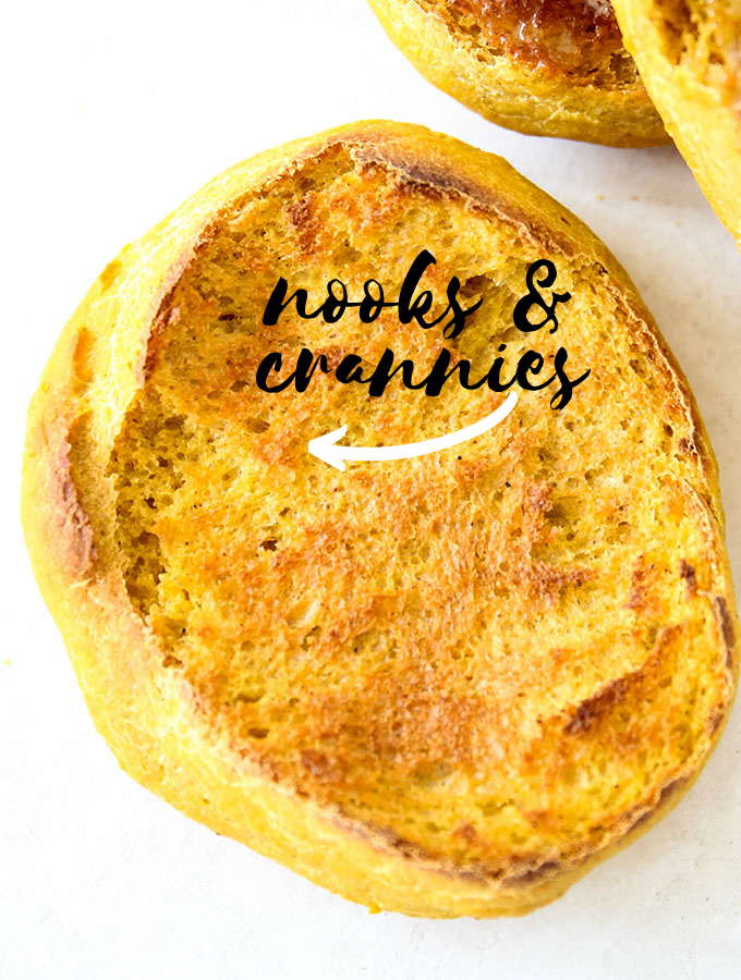 An English muffin is halved and there is an arrow pointing to the nooks and crannies in the muffin.