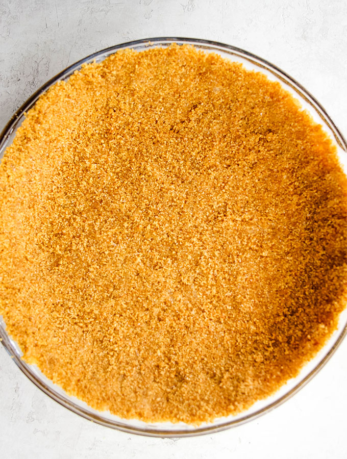 Graham cracker crust is made with cinnamon graham crackers and salted butter, then it is pressed in a glass dish.