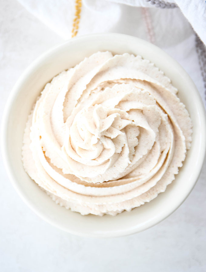 Cinnamon maple whipped cream is swirled into a bowl and plated onto of a napkin.