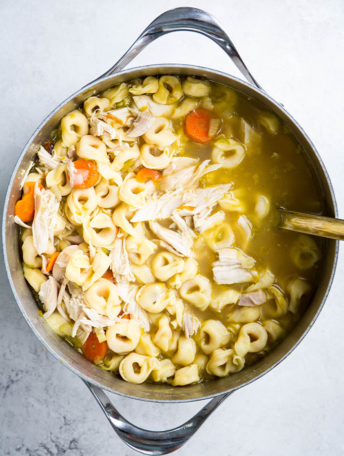 Tortellini chicken soup is made in one large bowl and spooned with a ladle.