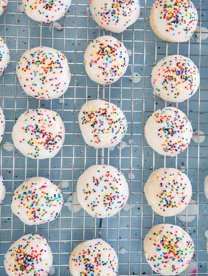 Italian anise cookies are glazed and topped with sprinkles, then left to dry.
