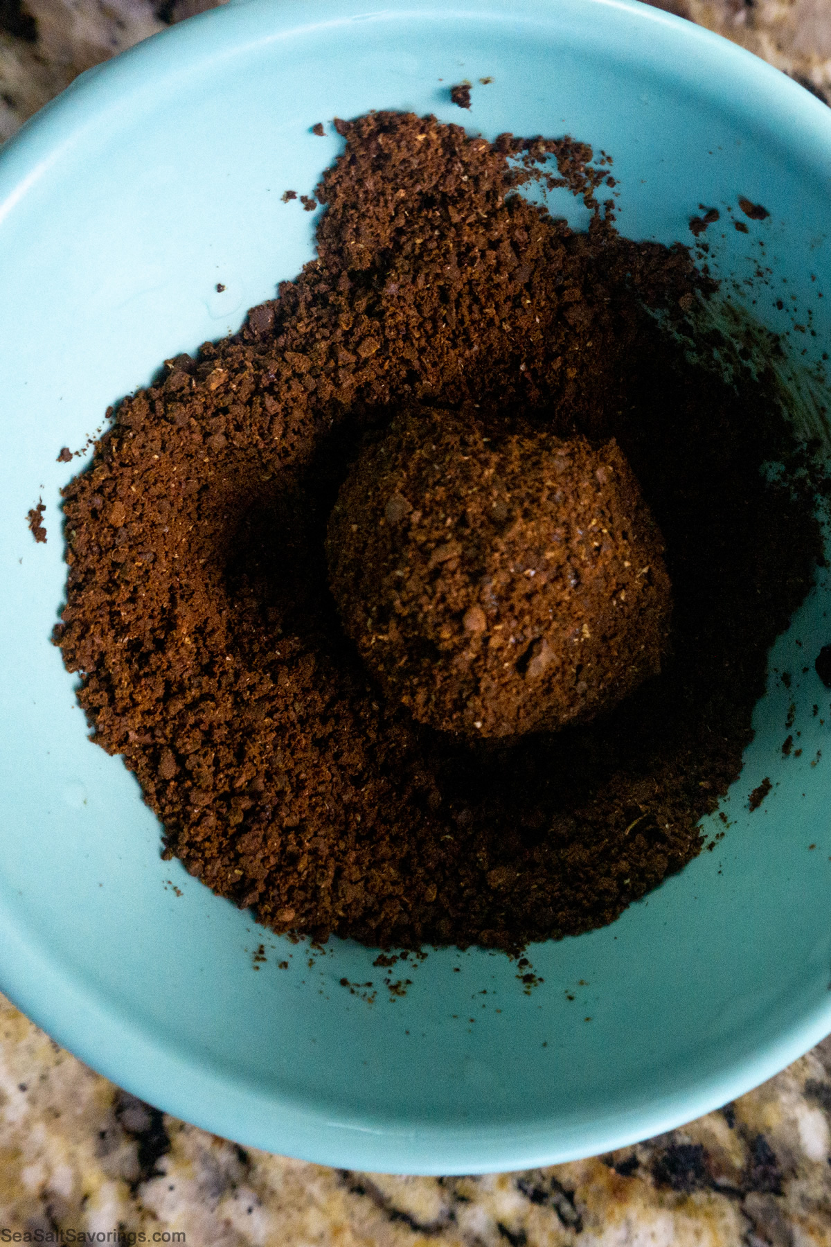 a ball of chocolate rolled in a bowl of espresso crumbs