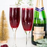 Pomegranate mimosas are placed in front of a bottle of Chandon champagne.