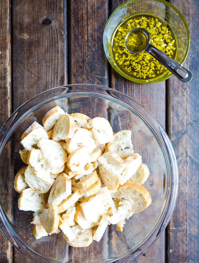 Bread is sliced and tossed in olive oil and garlic, then baked to make croutons.