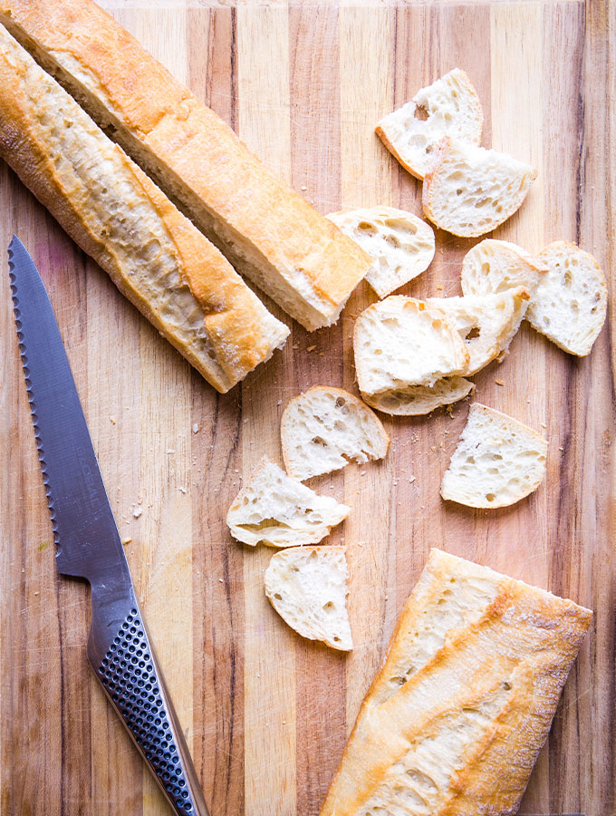 Bread is sliced into bite sized pieces to make homemade croutons.