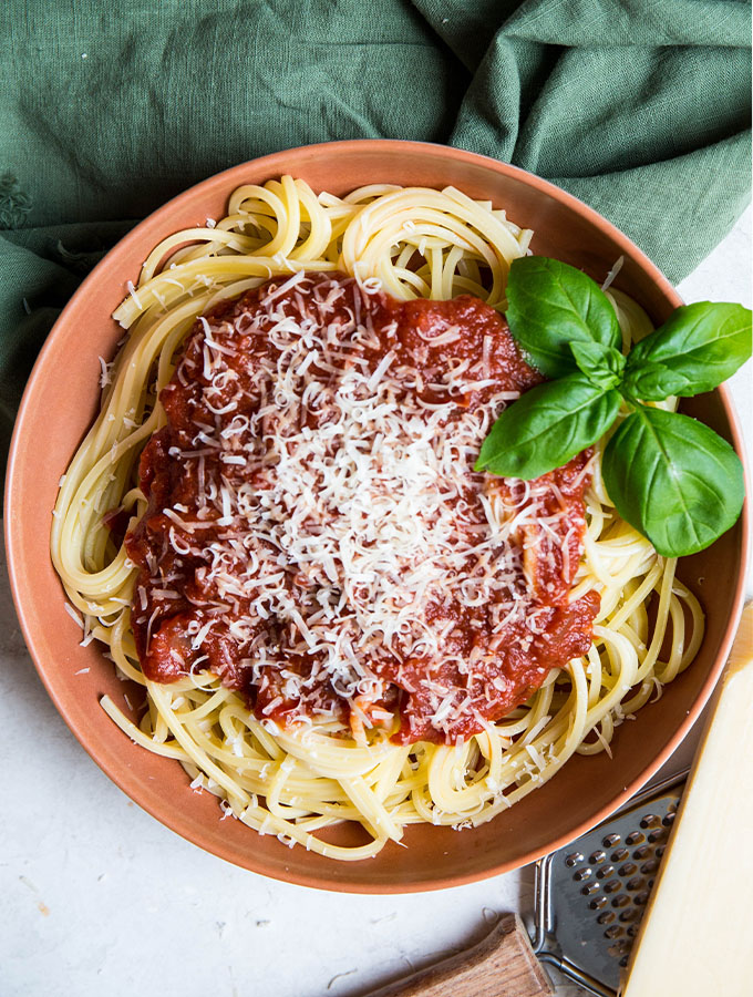 Spaghetti pasta is topped with red wine pasta sauce to show it's thick texture and deep color.