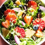 Winter salad is loaded with berries, citrus, onion, and salad dressing.