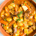 Gnocchi beef stew is topped with freshly cracked pepper and a sprig of thyme.