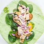 Italian chicken wrap is topped with chicken, spinach, red onion, and tomato.