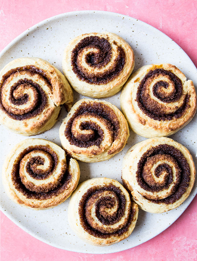 Cinnamon rolls are plated on a speckled plate after they are baked.