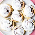 Cinnamon rolls are frosted with cream cheese frosting.