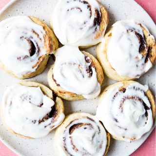 Cinnamon rolls are frosted with cream cheese frosting.