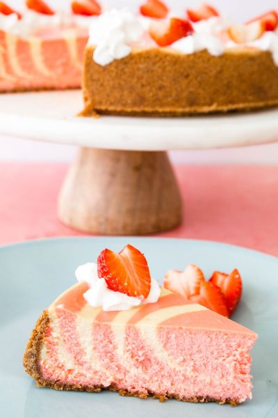 A slice of strawberries and cream cheesecake is plated on a blue plate.