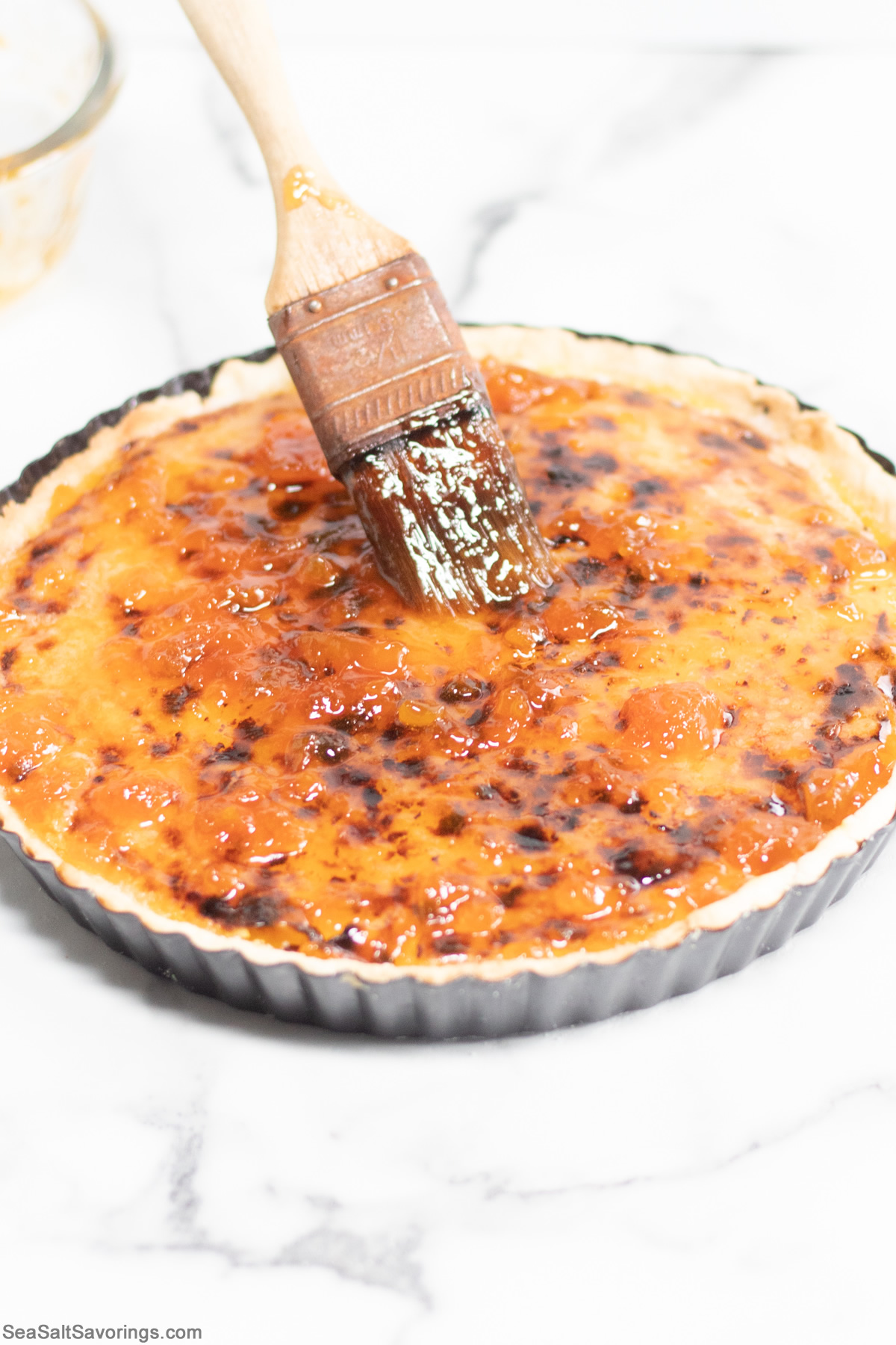 caramelized pie tart getting brushed with a topping