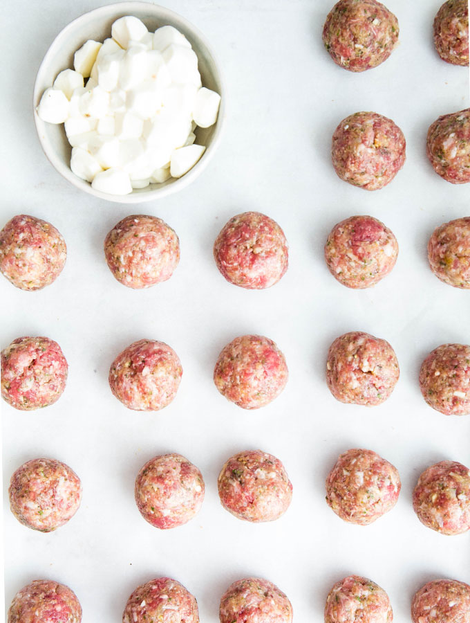 The meatballs are stuffed and shaped into balls and placed on a baking sheet.