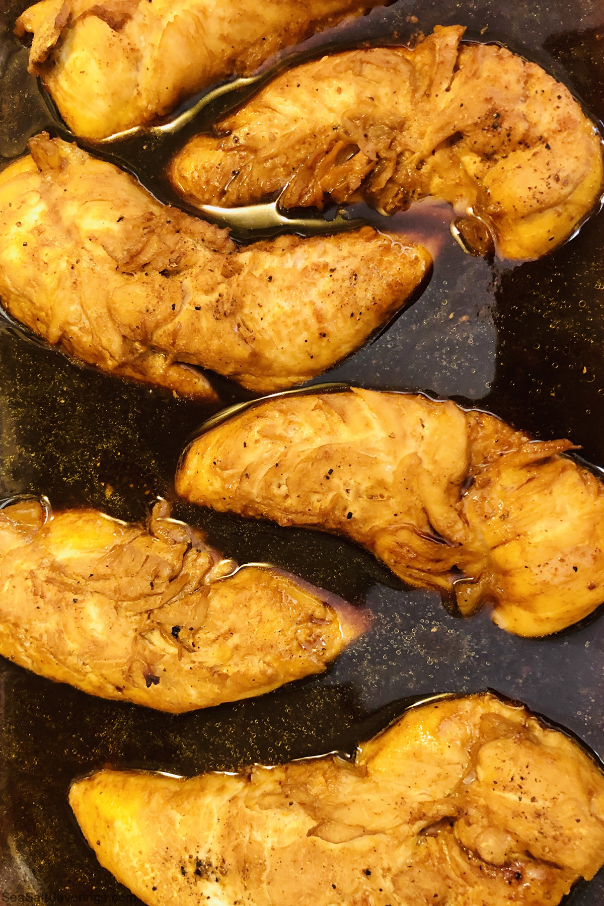 chicken breasts in a cooking pot while they cook in the marinade