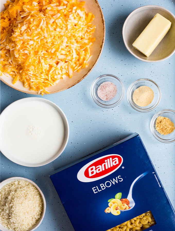 Mac and cheese ingredients are displayed individually on a blue baking sheet.